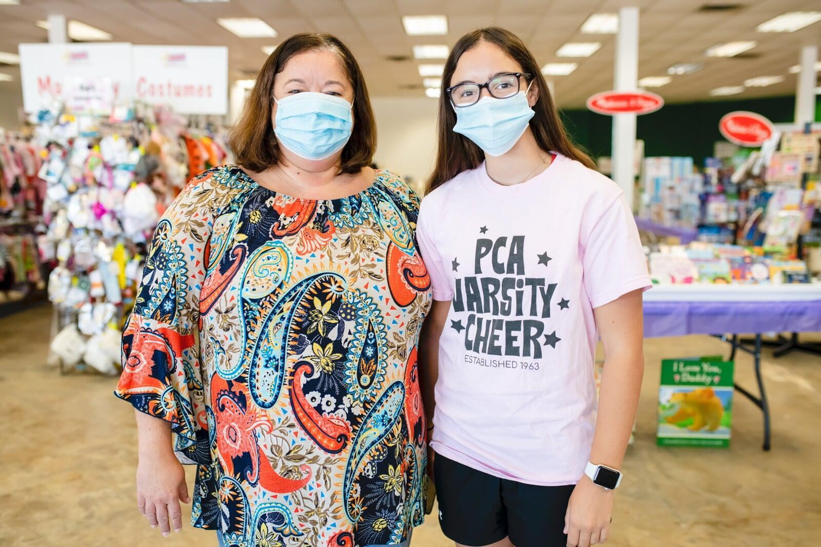A mother and daughter stand side by side in their masks as they shop their local JBF sale.